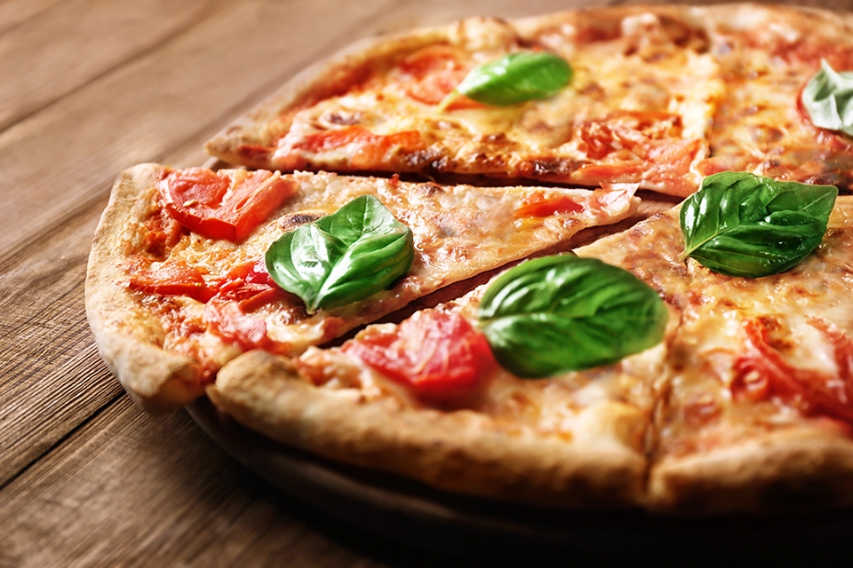 Bild einer Pizza mit Käse, Tomaten und Basilikum